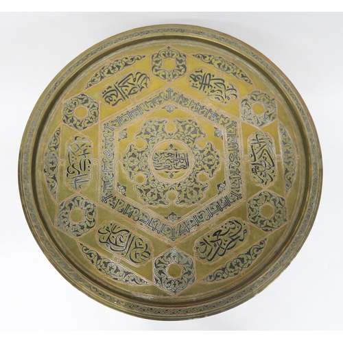 22 - AN EARLY 20TH CENTURY BRASS TOPPED FOLDING BENARES TABLEinlaid with copper and steel depicting Arabi... 