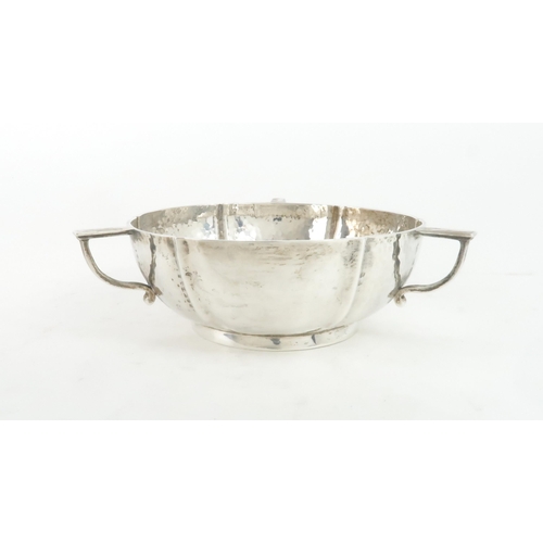 462 - AN EDWARDIAN SILVER THREE HANDLED BOWLthe body lobed, in the arts and crafts style, with hammered su... 