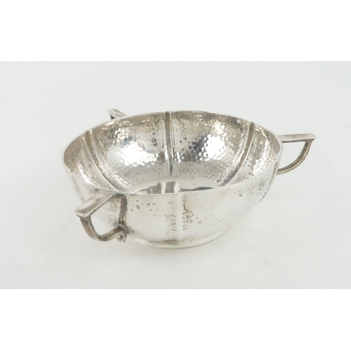 462 - AN EDWARDIAN SILVER THREE HANDLED BOWLthe body lobed, in the arts and crafts style, with hammered su... 