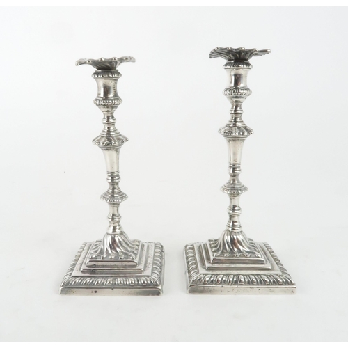 465 - A NEAR PAIR OF GEORGE III CAST SILVER CANDLESTICKSon square footed and gadrooned bases, with swirl c... 