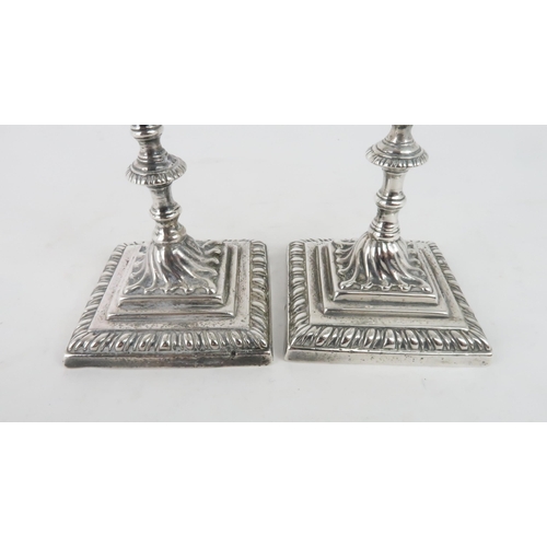 465 - A NEAR PAIR OF GEORGE III CAST SILVER CANDLESTICKSon square footed and gadrooned bases, with swirl c... 