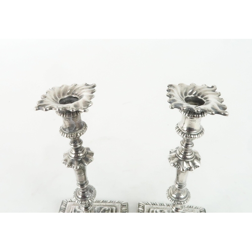 465 - A NEAR PAIR OF GEORGE III CAST SILVER CANDLESTICKSon square footed and gadrooned bases, with swirl c... 