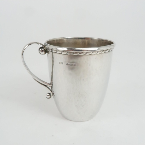 477 - A GEORG JENSEN SILVER CUPwith hammered surface finish and gadrooned edge, with a scrolling handle, i... 