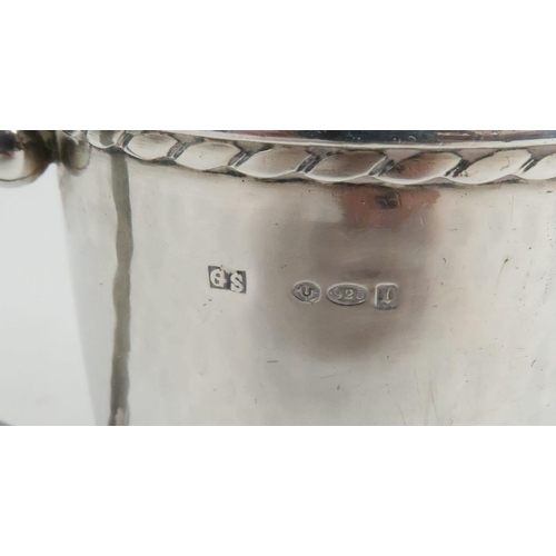 477 - A GEORG JENSEN SILVER CUPwith hammered surface finish and gadrooned edge, with a scrolling handle, i... 