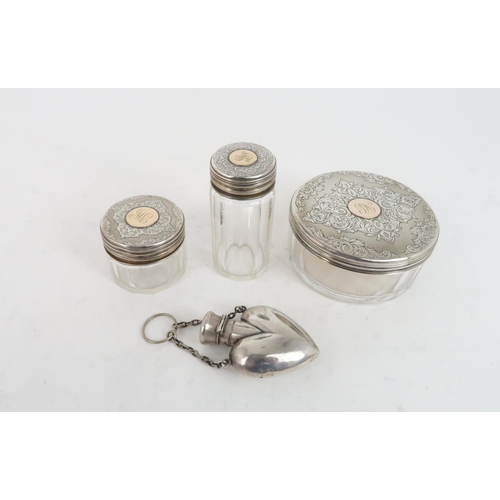 505 - A TRIO OF SILVER TOPPED GLASS VANITY JARSof faceted form, the lids with engraved scrolling decoratio... 