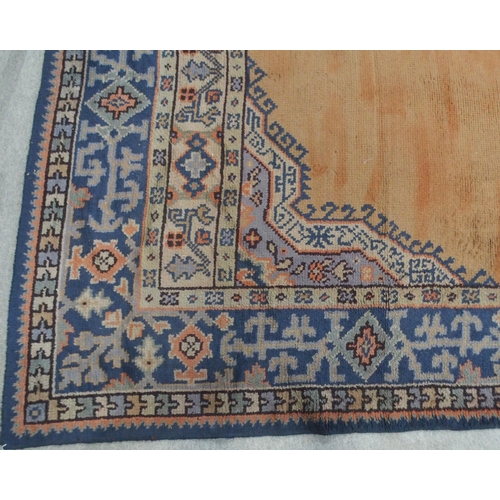 133 - A LARGE RUST GROUND MIDDLE EASTERN CARPETwith cream spandrels and blue geometric borders, 464cm long... 