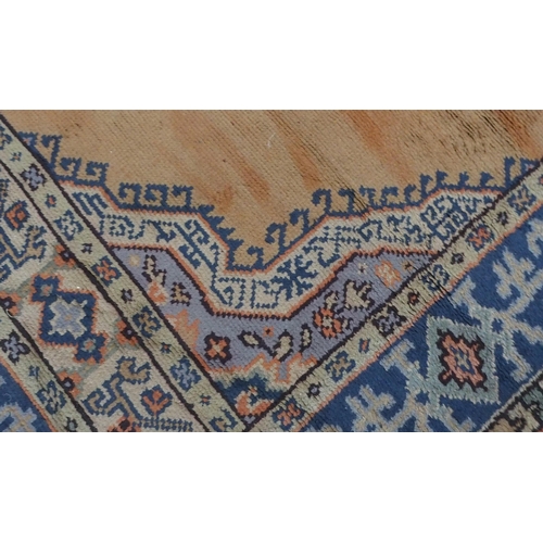 133 - A LARGE RUST GROUND MIDDLE EASTERN CARPETwith cream spandrels and blue geometric borders, 464cm long... 