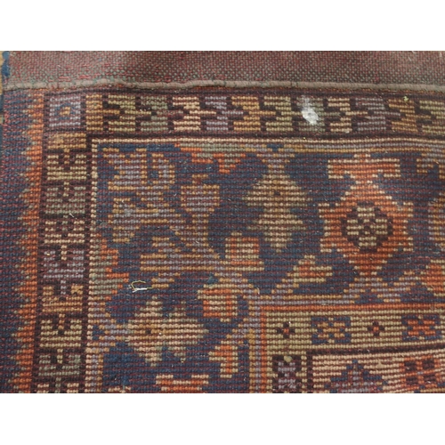 133 - A LARGE RUST GROUND MIDDLE EASTERN CARPETwith cream spandrels and blue geometric borders, 464cm long... 