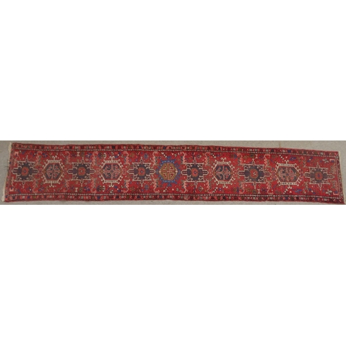 134 - A RED GROUND HERIZ RUNNERwith geometric medallions, 394cm long x 64cm wide