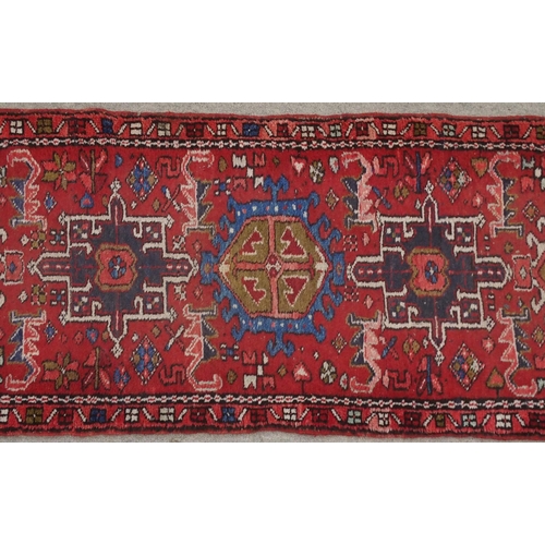 134 - A RED GROUND HERIZ RUNNERwith geometric medallions, 394cm long x 64cm wide