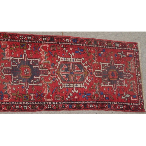 134 - A RED GROUND HERIZ RUNNERwith geometric medallions, 394cm long x 64cm wide