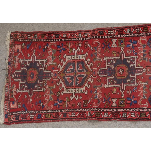 134 - A RED GROUND HERIZ RUNNERwith geometric medallions, 394cm long x 64cm wide