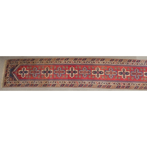 135 - A RED GROUND TURKISK DOSEMEALTI RUNNERwith multicoloured geometric medallions, dark blue spandrels a... 