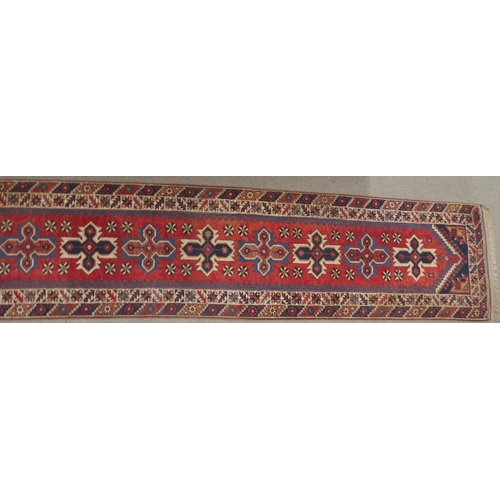 135 - A RED GROUND TURKISK DOSEMEALTI RUNNERwith multicoloured geometric medallions, dark blue spandrels a... 