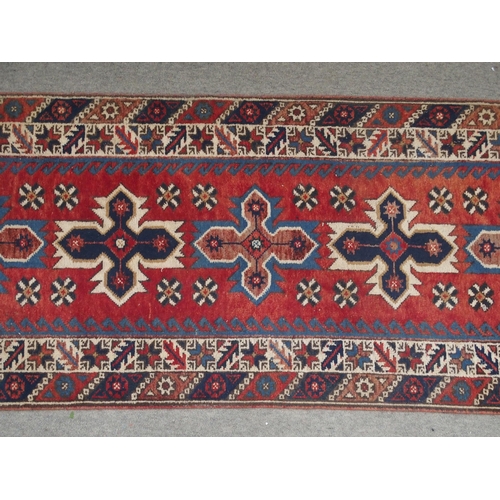 135 - A RED GROUND TURKISK DOSEMEALTI RUNNERwith multicoloured geometric medallions, dark blue spandrels a... 