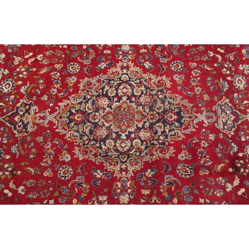 138 - A RED GROUND KESHAN RUGwith blue central medallion, matching spandrels and borders, signature to one... 