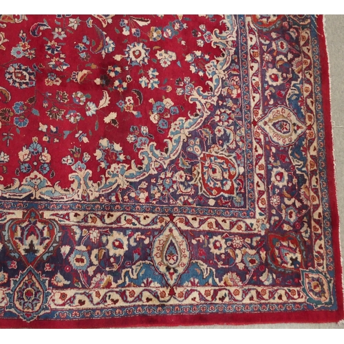 138 - A RED GROUND KESHAN RUGwith blue central medallion, matching spandrels and borders, signature to one... 