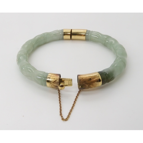 866 - A CHINESE GREEN HARDSTONE BANGLEcarved to look like bamboo, with 14k gold clasp and hinge. Inner dia... 