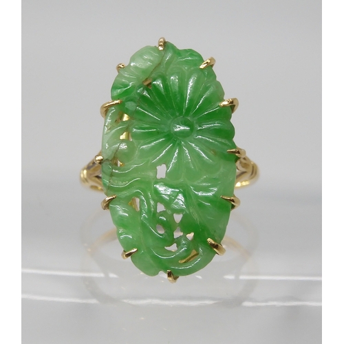 871 - AN 18CT GOLD CHINESE GREEN HARDSTONE RINGcarved with a chrysanthemum and foliage, claw set to the pi... 