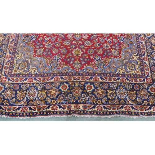 132A - A RED GROUND MESHED RUGwith floral central medallion, matching spandrels and dark blue floral border... 