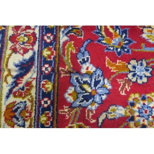 132A - A RED GROUND MESHED RUGwith floral central medallion, matching spandrels and dark blue floral border... 