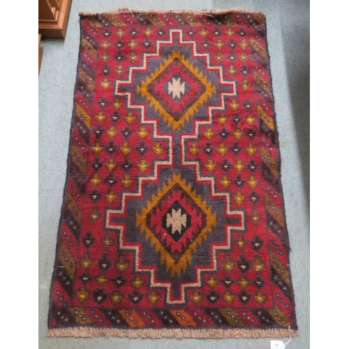 3 - A red ground Balouch rug with dual central medallion and multicoloured border, 134cm long x 86cm wid... 