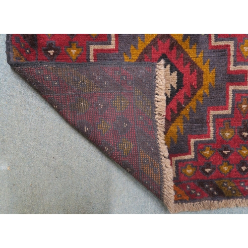 3 - A red ground Balouch rug with dual central medallion and multicoloured border, 134cm long x 86cm wid... 