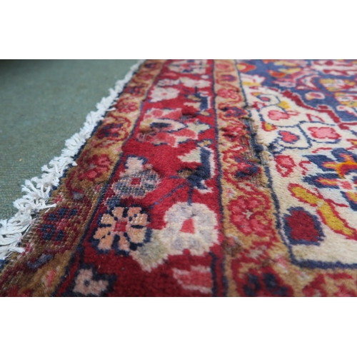 44 - A dark blue ground Persian rug with red central medallion, cream spandrels and red floral borders, 2... 