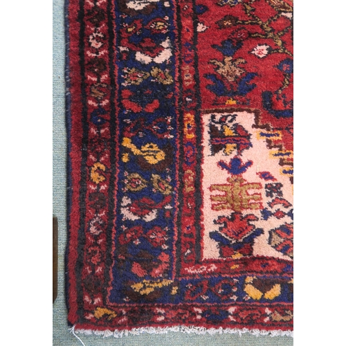 100 - A red ground Iranian Hamedan runner with dark blue borders, 175cm long x 101cm wide