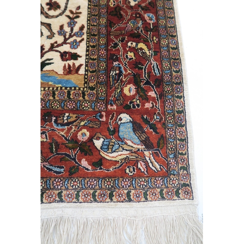 102 - AN EASTERN SILK CREAM GROUND RUG DEPICTING A HUNTING SCENE