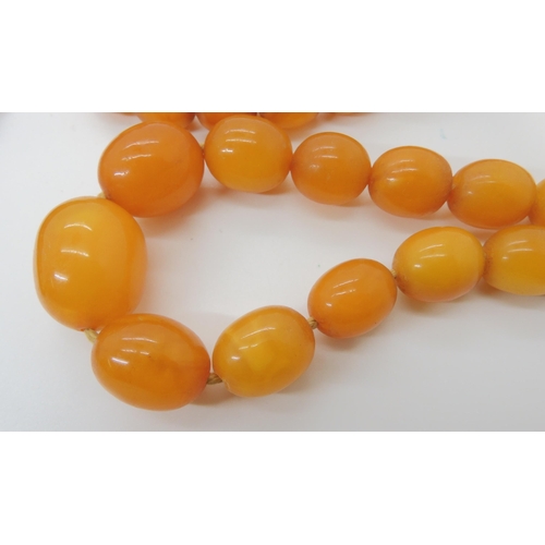 548 - A STRING OF AMBER BEADS AND A STRING OF HORN BEADS