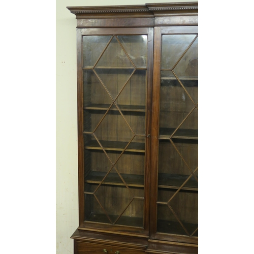 1 - A MAHOGANY BREAKFRONT BOOKCASE the dentil cornice above four astragal doors  encclosing shelves and ... 