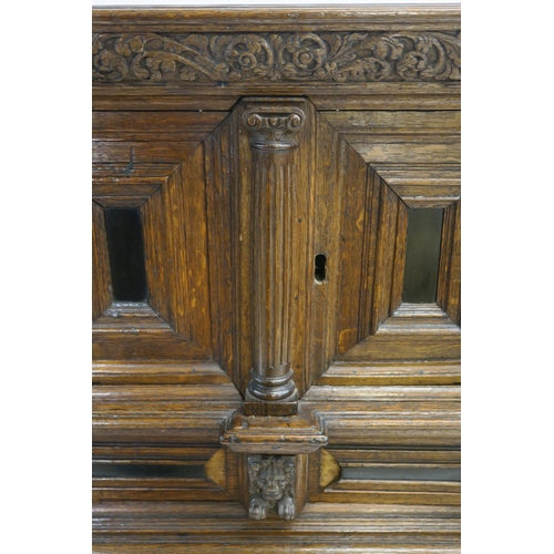 4 - A CONTINENTAL OAK AND EBONY CABINET AND STAND with a panelled drawer applied with lion brackets abov... 