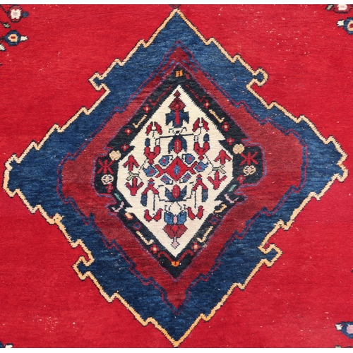 94 - A RED GROUND EASTERN RUG WITH CENTRAL MEDALLION