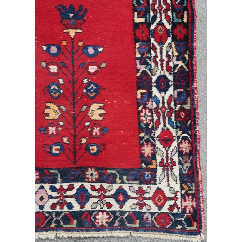 94 - A RED GROUND EASTERN RUG WITH CENTRAL MEDALLION