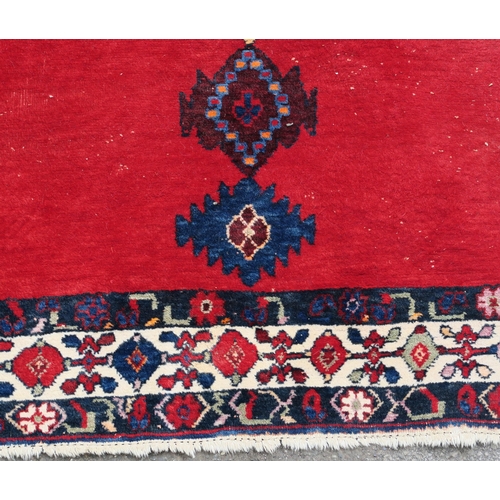 94 - A RED GROUND EASTERN RUG WITH CENTRAL MEDALLION