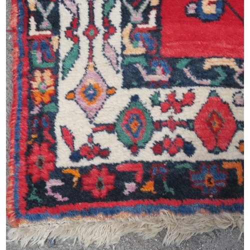 94 - A RED GROUND EASTERN RUG WITH CENTRAL MEDALLION