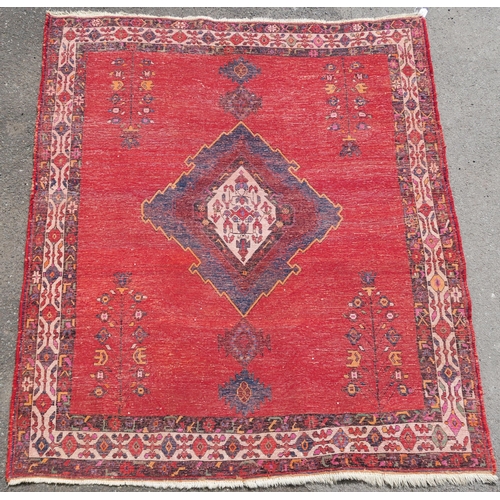 94 - A RED GROUND EASTERN RUG WITH CENTRAL MEDALLION