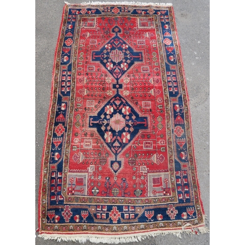 95 - A RED GROUND EASTERN RUG WITH TWO BLUE CENTRAL LOZENGES