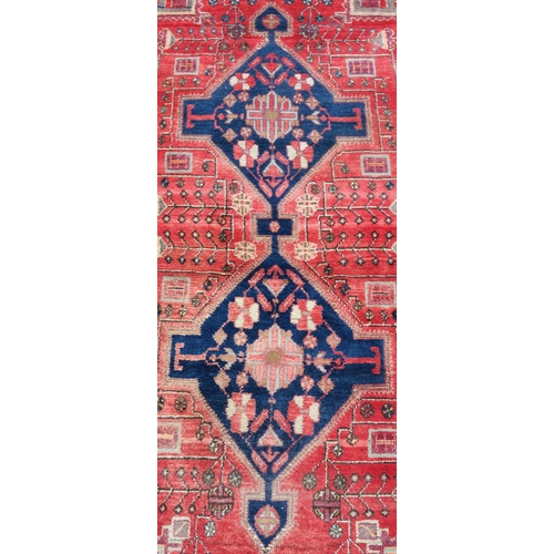 95 - A RED GROUND EASTERN RUG WITH TWO BLUE CENTRAL LOZENGES