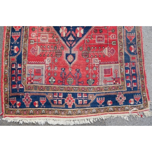 95 - A RED GROUND EASTERN RUG WITH TWO BLUE CENTRAL LOZENGES