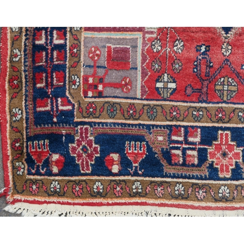 95 - A RED GROUND EASTERN RUG WITH TWO BLUE CENTRAL LOZENGES