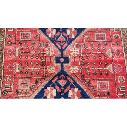 95 - A RED GROUND EASTERN RUG WITH TWO BLUE CENTRAL LOZENGES