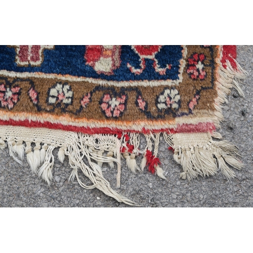 95 - A RED GROUND EASTERN RUG WITH TWO BLUE CENTRAL LOZENGES