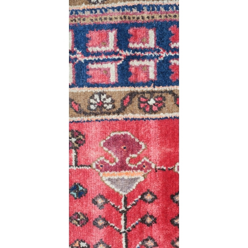 95 - A RED GROUND EASTERN RUG WITH TWO BLUE CENTRAL LOZENGES