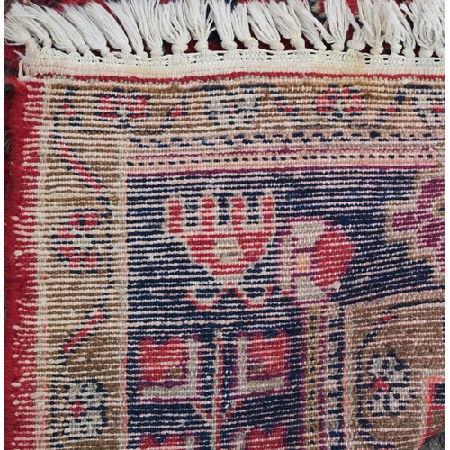 95 - A RED GROUND EASTERN RUG WITH TWO BLUE CENTRAL LOZENGES