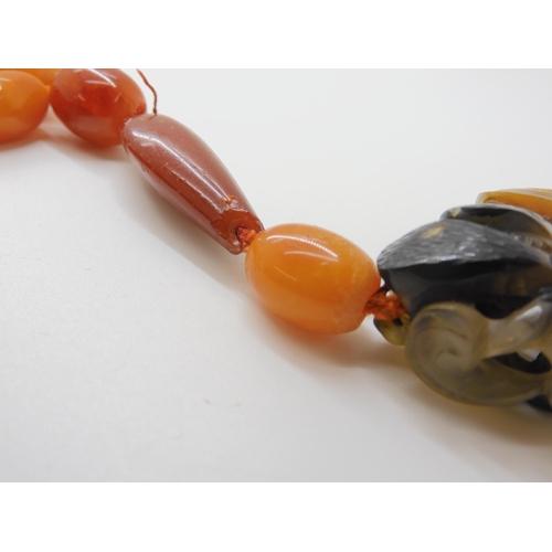 560 - A STRING OF AMBER BEADS WITH A CHINESE CARVED PENDANT