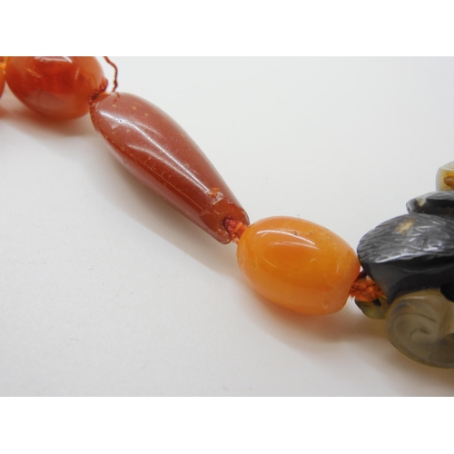 560 - A STRING OF AMBER BEADS WITH A CHINESE CARVED PENDANT