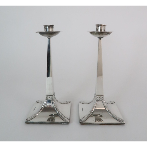 719 - A PAIR OF ARTS AND CRAFTS SILVER CANDLESTICKS