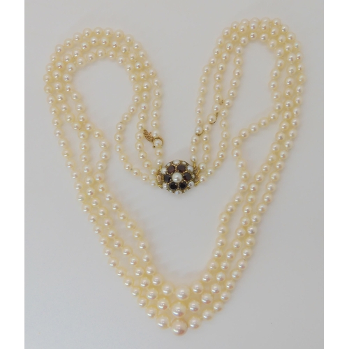 516 - THREE STRANDS OF PEARLS WITH A GOLD AND GARNET CLASP